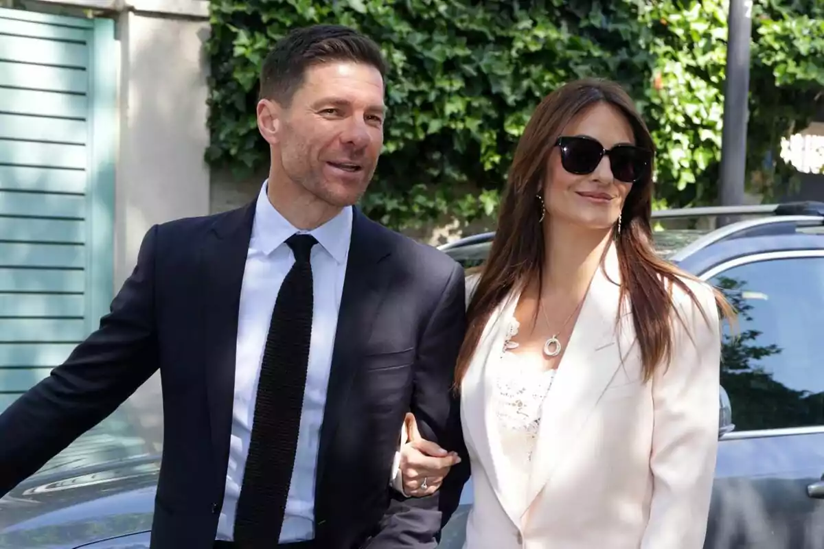 Parella elegantament vestida caminant a l’aire lliure al costat d’un cotxe i vegetació de fons Parella elegantament vestida caminant a l’aire lliure al costat d’un cotxe i vegetació de fons