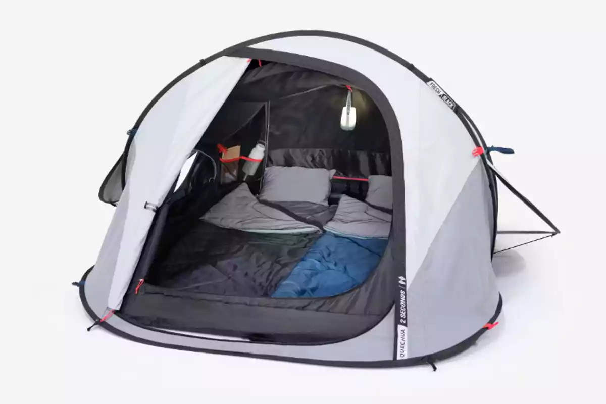 Tenda de campanya grisa muntada amb l’entrada oberta mostrant dos sacs de dormir i coixins a l’interior Tenda de campanya grisa muntada amb l’entrada oberta mostrant dos sacs de dormir i coixins a l’interior