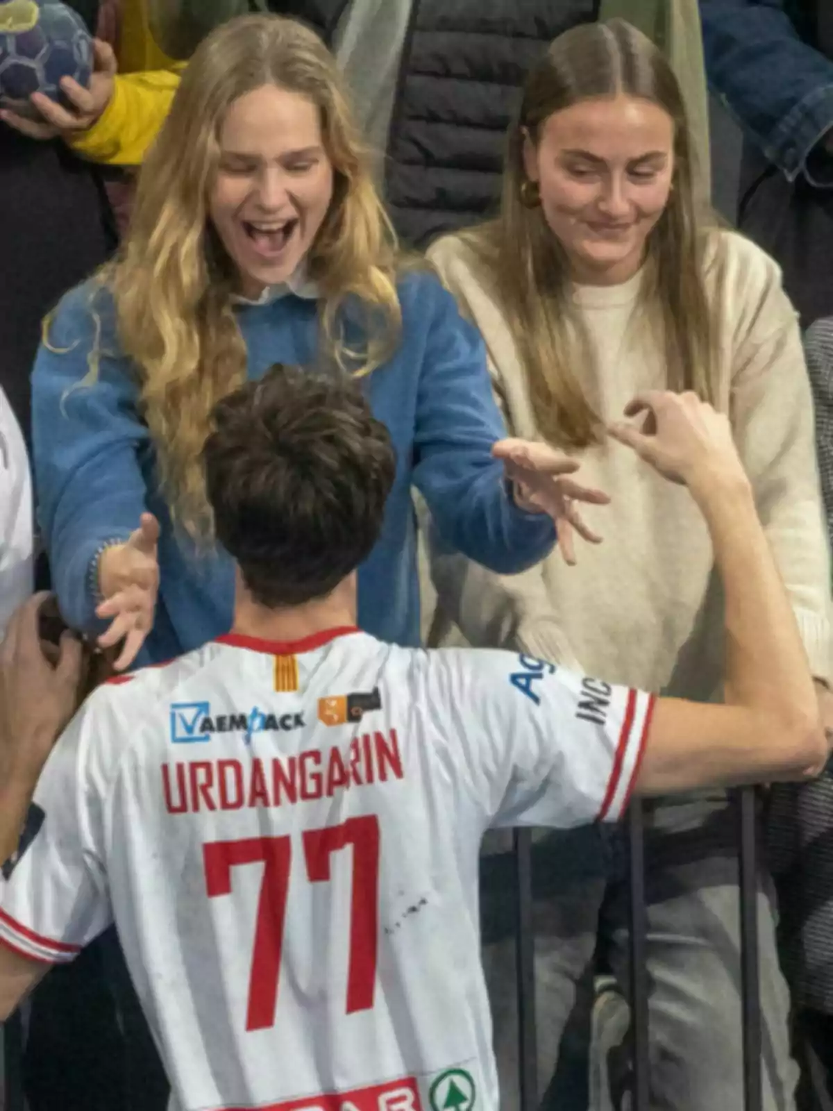 Pablo Urdangarin amb la samarreta número 77 celebra amb Irene Urdangarin i Johanna Zott a la graderia, que mostren alegria i emoció.