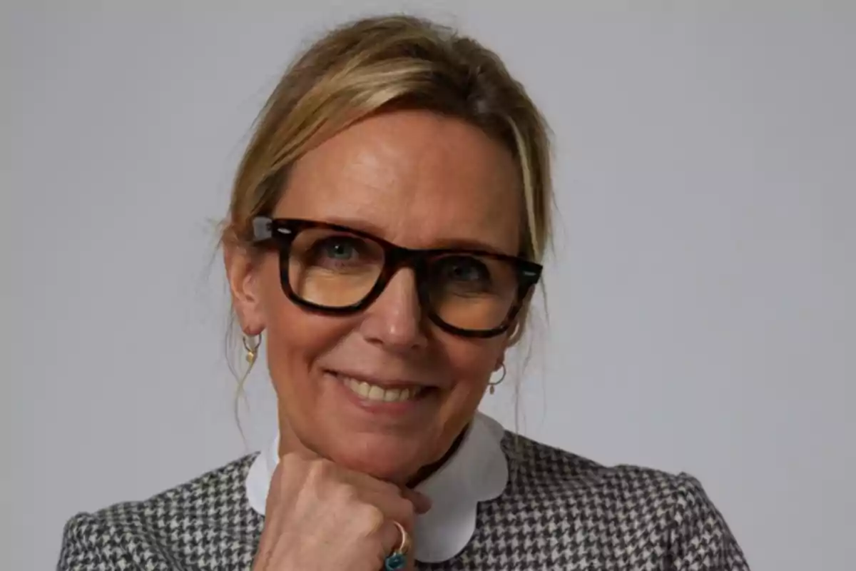 Jet Shenkman with large glasses and a smile, resting her chin on her hand, wearing a white-collared blouse and a plaid jacket. Jet Shenkman with large glasses and a smile, resting her chin on her hand, wearing a white-collared blouse and a plaid jacket.