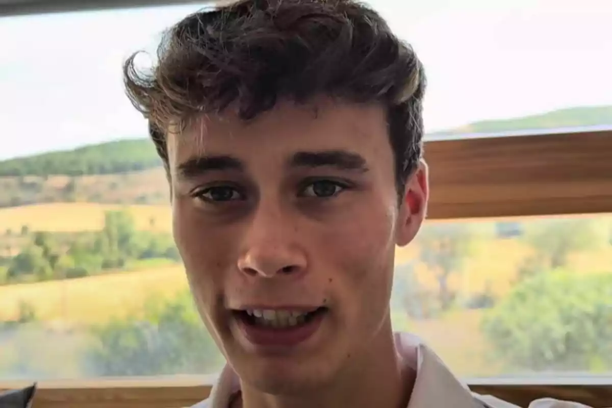 Pla curt de Jorge Rey amb els cabells castanys i ulls clars mirant a la càmera amb un paisatge de camp al fons.