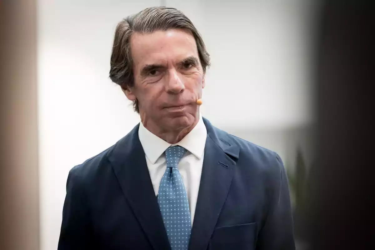 José María Aznar amb vestit blau i corbata cel utilitzant un micròfon de diadema José María Aznar amb vestit blau i corbata cel utilitzant un micròfon de diadema