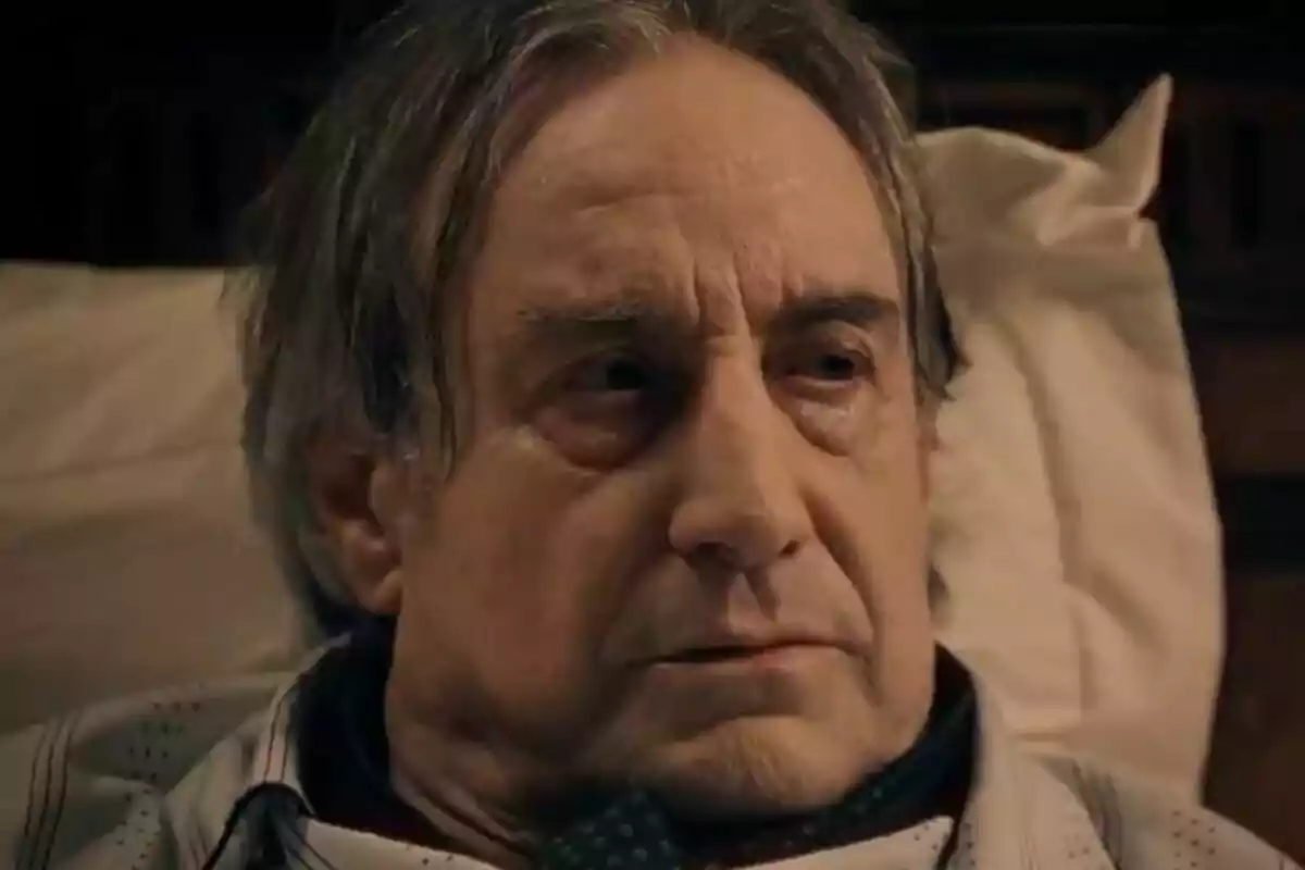 Primer pla de Juanjo Puigcorbé estirat en un llit amb expressió seriosa i cabells canosos despentinats. Primer pla de Juanjo Puigcorbé estirat en un llit amb expressió seriosa i cabells canosos despentinats.