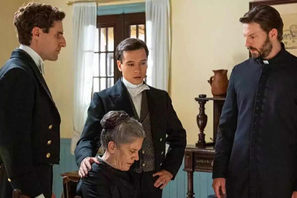 Lope, Curro, Samuel i Petra amb vestimenta d’època són en una habitació, tres homes drets envolten una dona asseguda que sembla estar trista o preocupada. Captura de ‘La Promesa’ Lope, Curro, Samuel i Petra amb vestimenta d’època són en una habitació, tres homes drets envolten una dona asseguda que sembla estar trista o preocupada. Captura de ‘La Promesa’