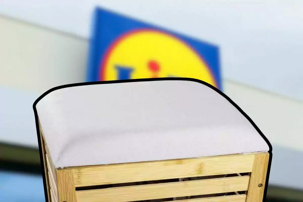 Banc de fusta amb coixí blanc davant d’un rètol borros de supermercat