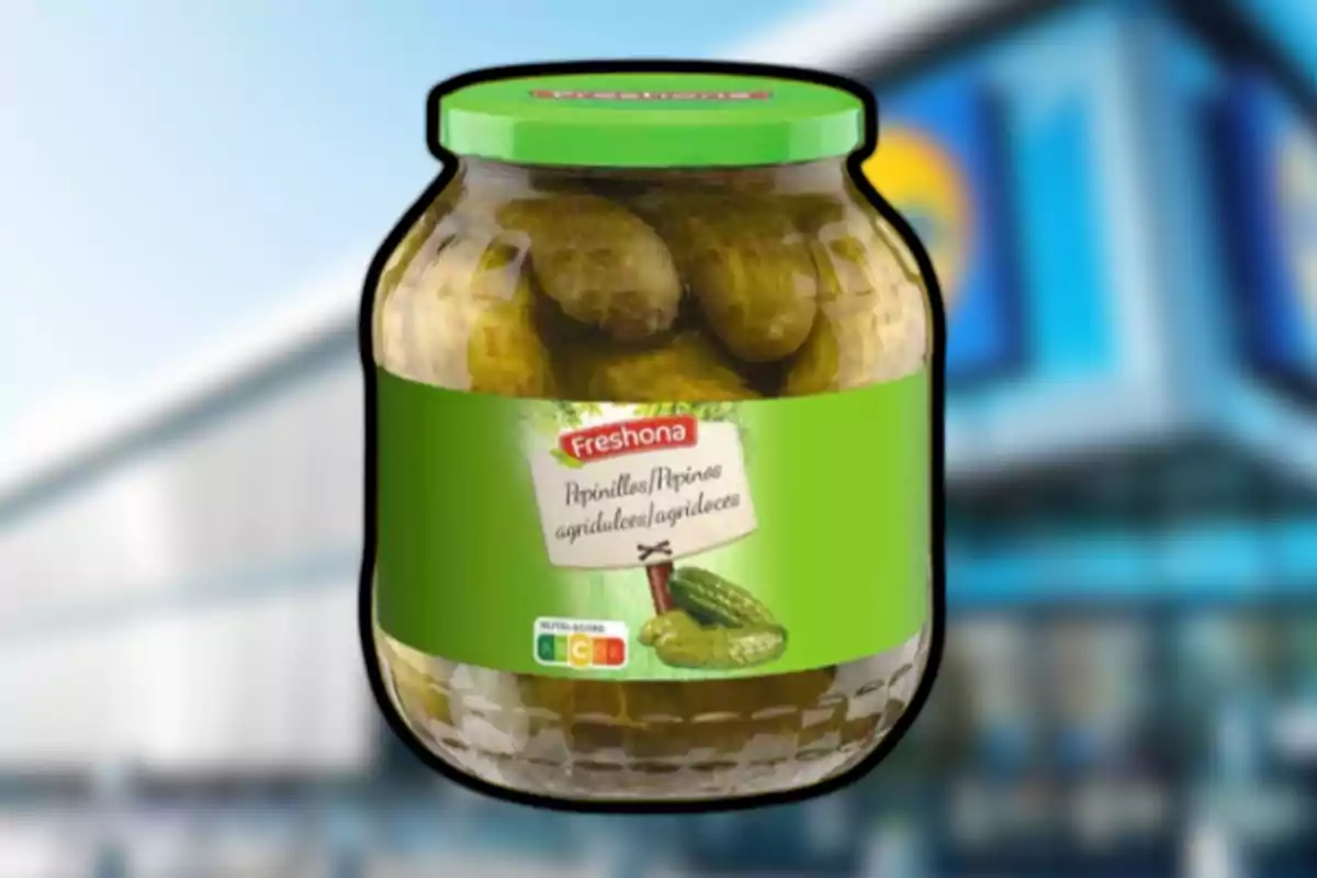 Pot de cogombrets agredolços de la marca Freshona amb tapa verda sobre un fons desenfocat de supermercat