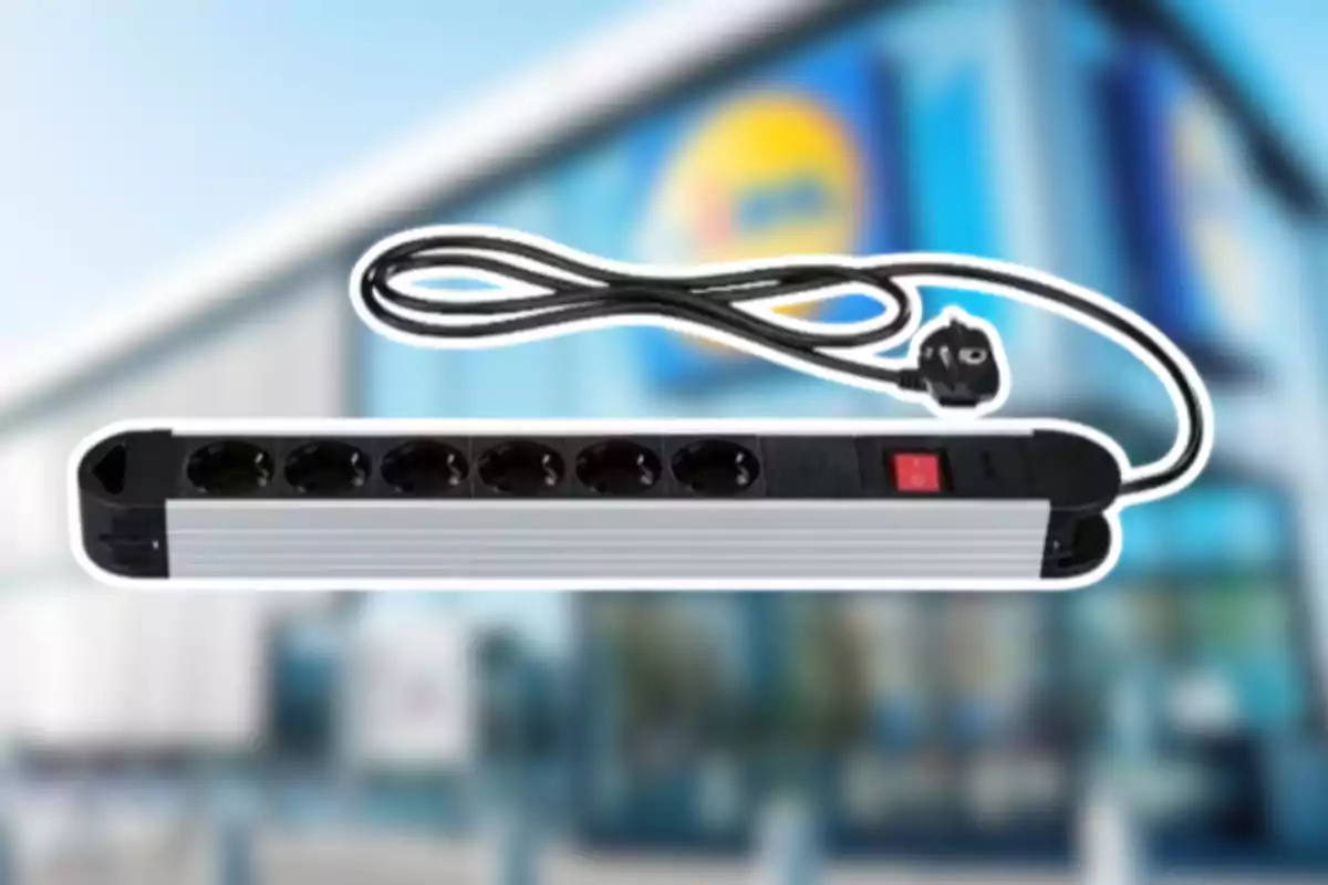 Regleta elèctrica de sis endolls amb interruptor i cable negre sobre un fons desenfocat d’una botiga Regleta elèctrica de sis endolls amb interruptor i cable negre sobre un fons desenfocat d’una botiga