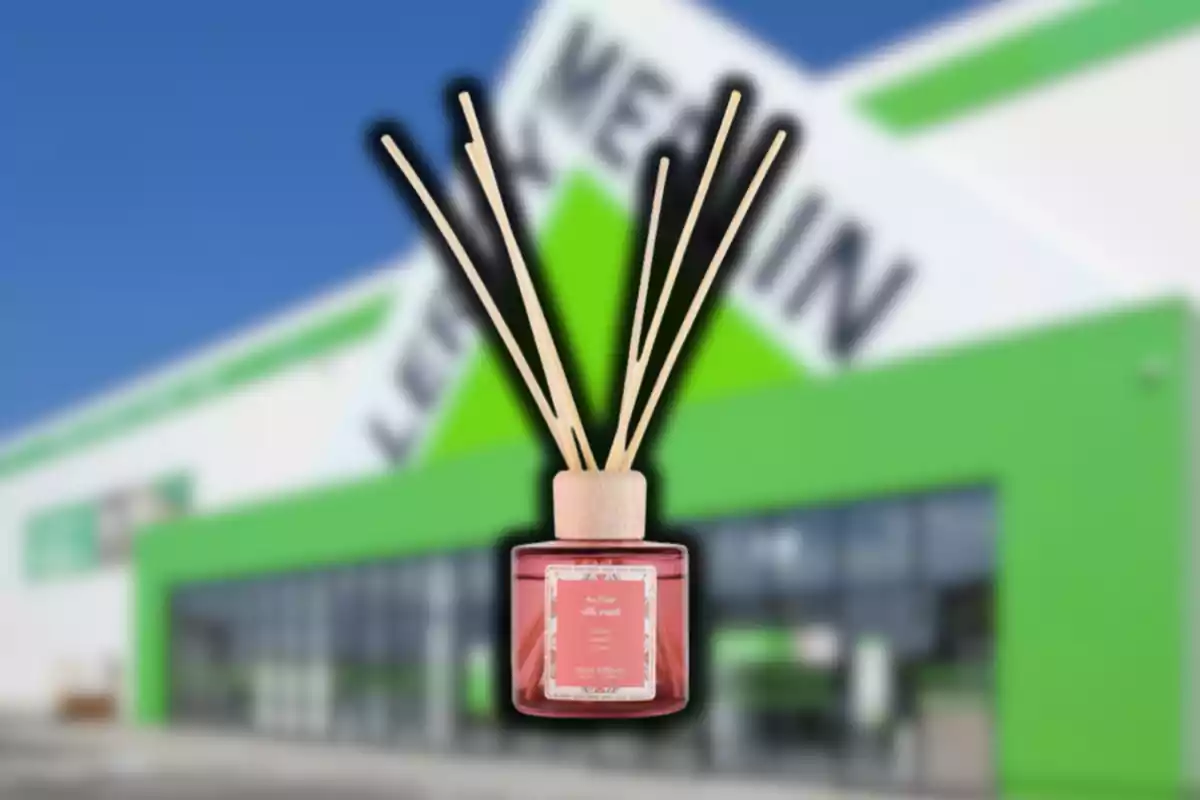 Difusor de varetes amb líquid aromàtic en primer pla sobre un fons desenfocat d’una botiga amb façana verda i blanca Difusor de varetes amb líquid aromàtic en primer pla sobre un fons desenfocat d’una botiga amb façana verda i blanca