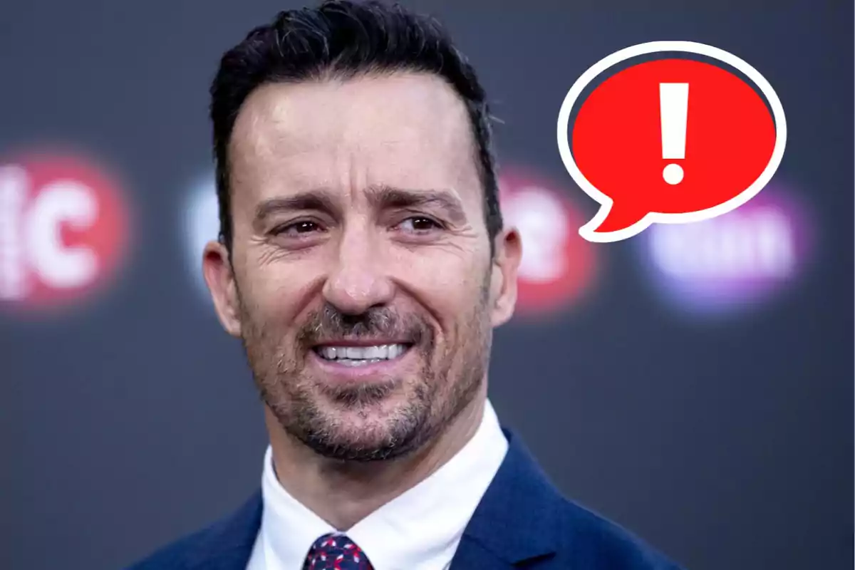 Pablo Puyol, with dark hair, a beard, and a suit, smiles as a red speech bubble with a white exclamation mark appears.