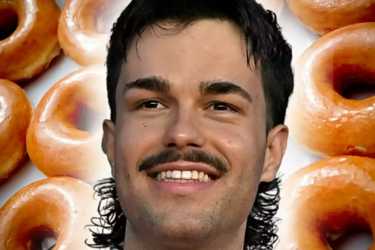 Primer plano de Peldanyos sonriendo frente a un fondo de donuts glaseados.