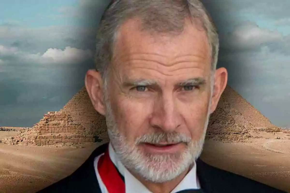 El rei Felip amb cabells canosos i barba davant de dues piràmides en un paisatge desèrtic sota un cel ennuvolat