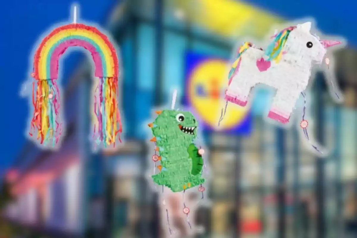 Tres colorides piñates amb forma d’arc de Sant Martí, dinosaure i unicorn estan suspeses davant d’un edifici desenfocat.