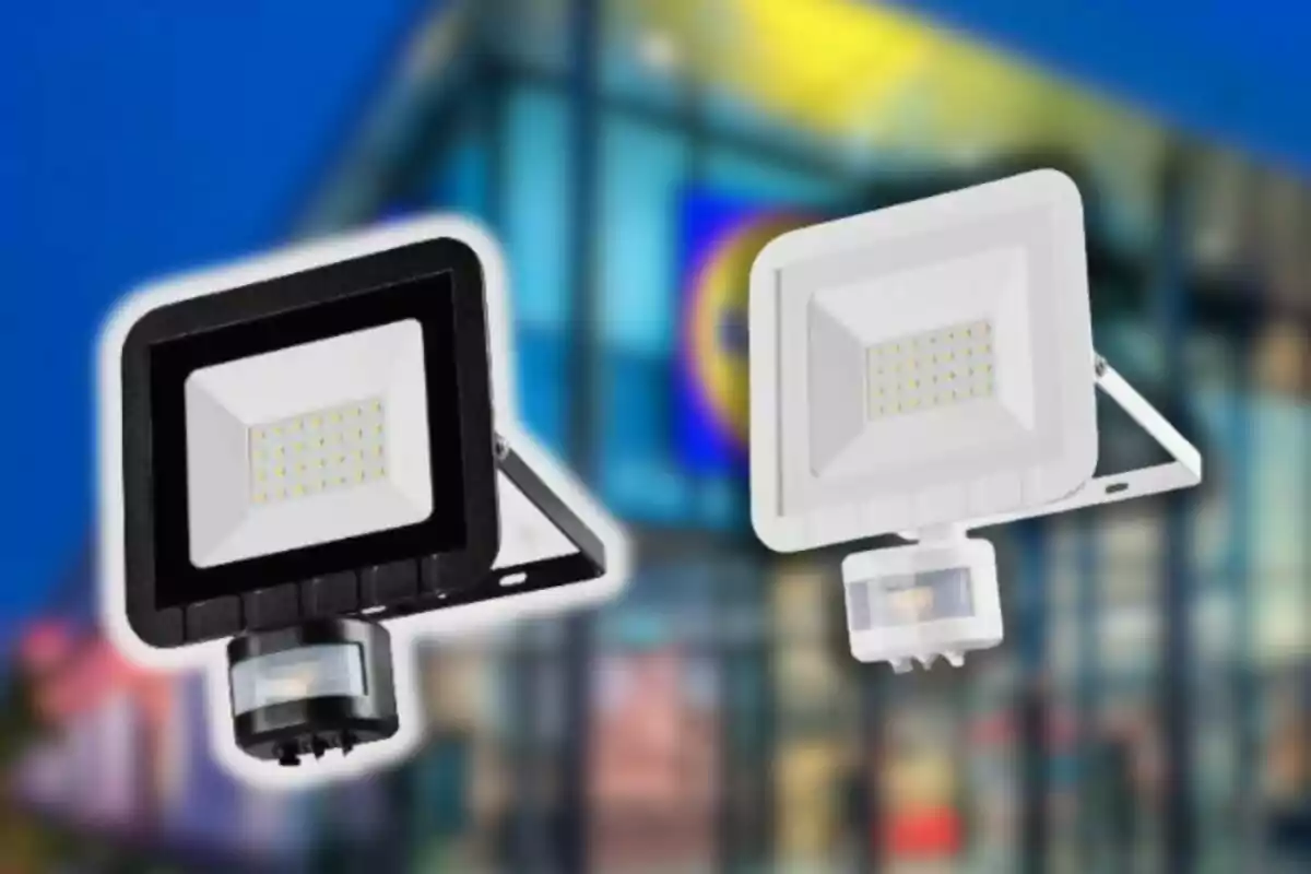 Dos focus LED, un de negre i un de blanc, amb sensor de moviment davant d’un edifici modern desenfocat