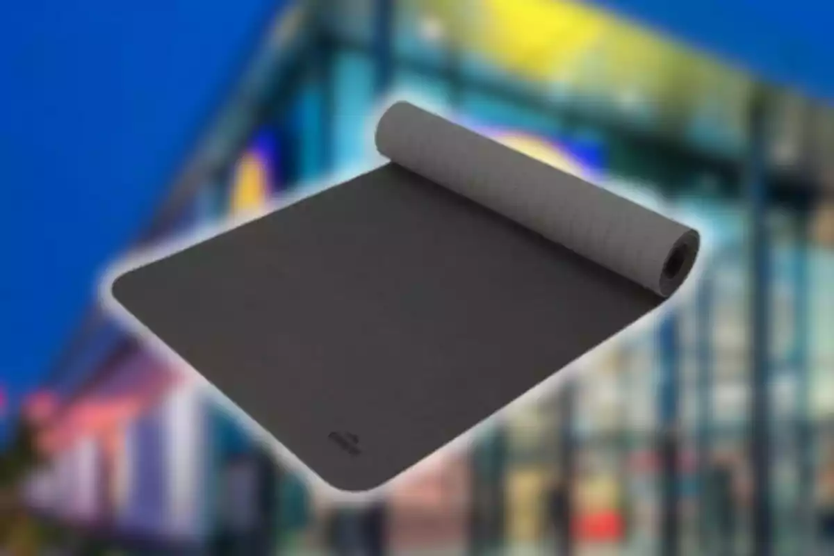 Tapete de yoga gris parcialmente enrollado con fondo de edificio desenfocado