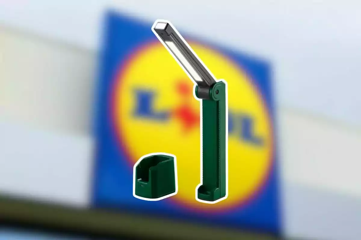 Làmpada d’escriptori plegable de color verd amb base, sobre un fons desenfocat d’un rètol de supermercat