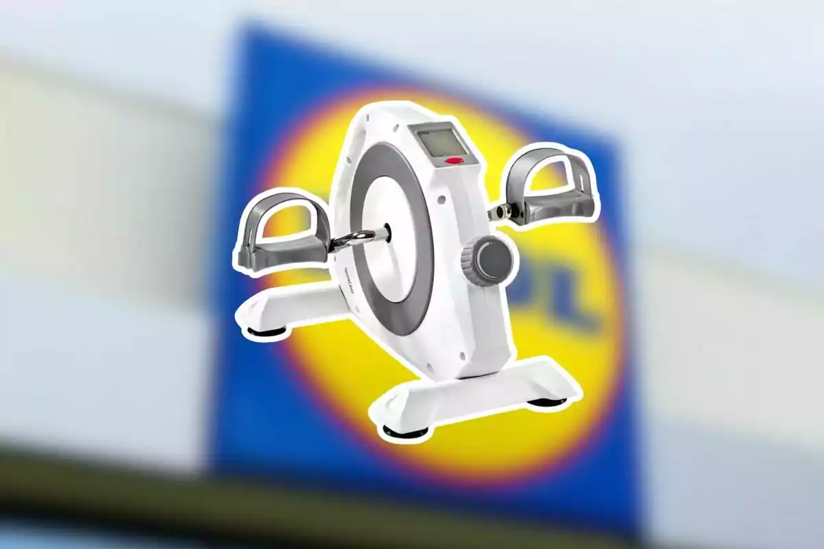 Pedalejador blanc amb pantalla digital i pedals grisos sobre un fons desenfocat d’un rètol de supermercat Pedalejador blanc amb pantalla digital i pedals grisos sobre un fons desenfocat d’un rètol de supermercat