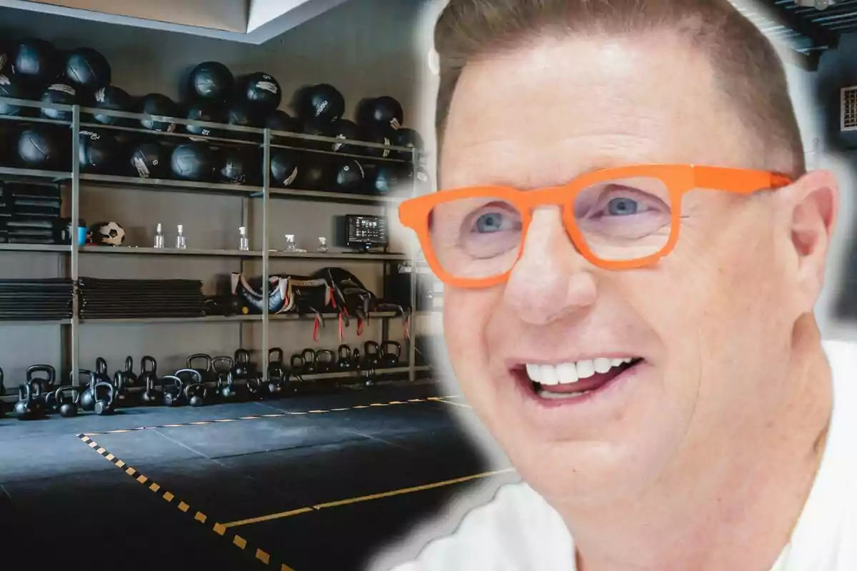 Jorge Cadaval con gafas naranjas sonriente en primer plano con fondo de gimnasio equipado con pesas, balones y colchonetas.