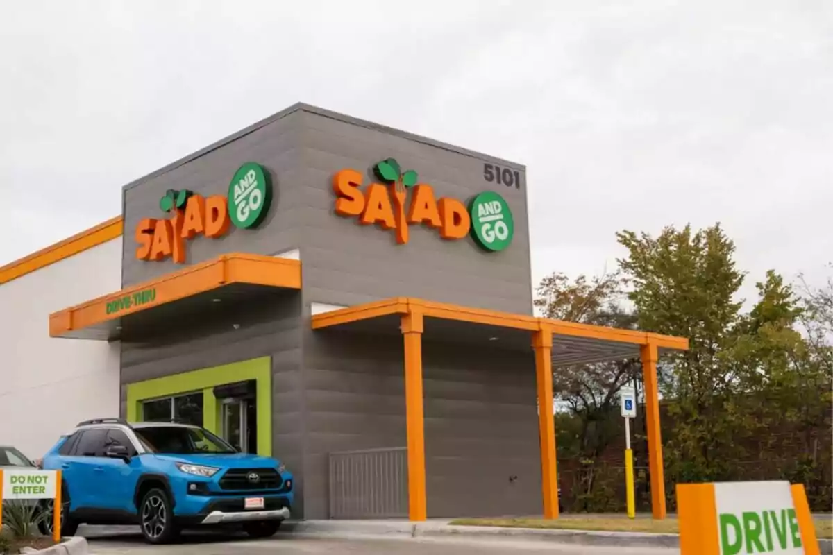 Salad and Go fast food restaurant with a blue car in the drive-thru and green and orange signs