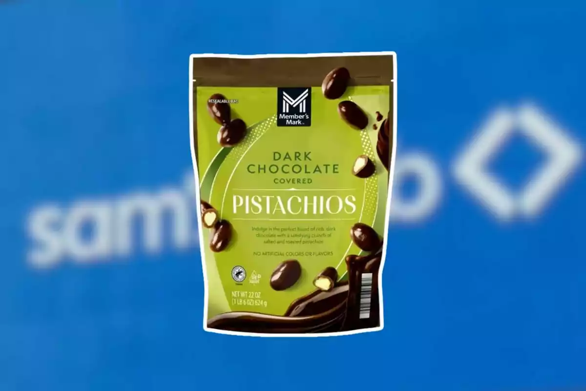 Bag of Member’s Mark dark chocolate covered pistachios on a blurred blue background.