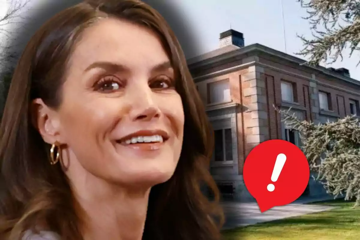 La reina Letizia sonriente en primer plano con una casa de ladrillo al fondo y un icono de advertencia rojo