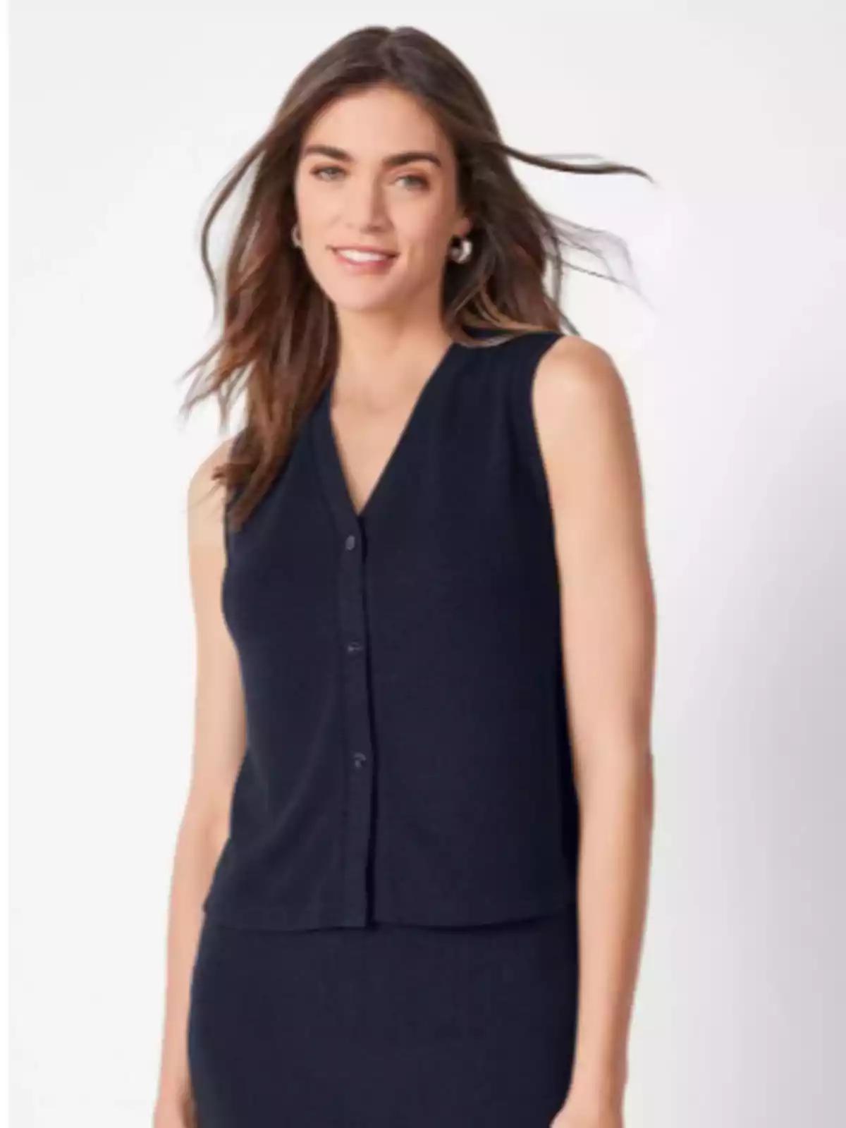 Dona jove amb cabell solt i ondulat portant un top negre de tirants i una faldilla a joc, posant davant d’un fons clar. Dona jove amb cabell solt i ondulat portant un top negre de tirants i una faldilla a joc, posant davant d’un fons clar.