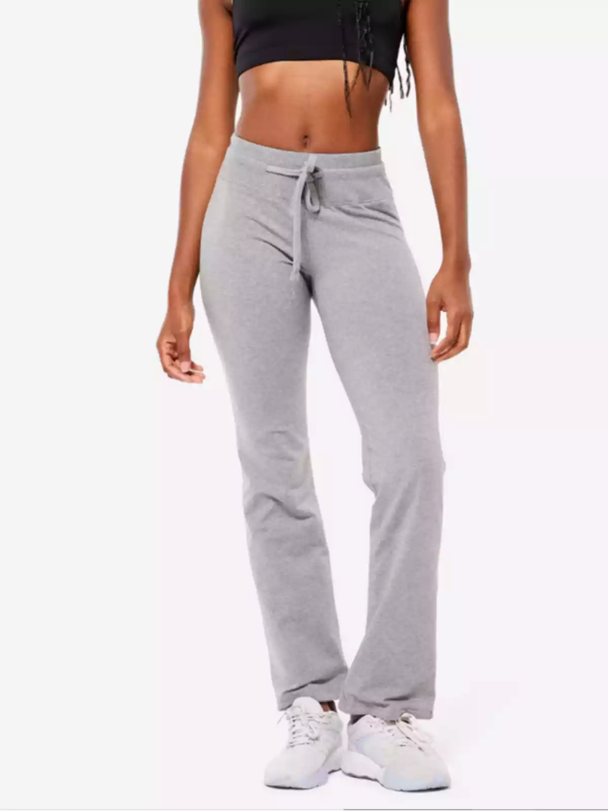 Dona amb pantalons esportius grisos i top negre amb vambes blanques