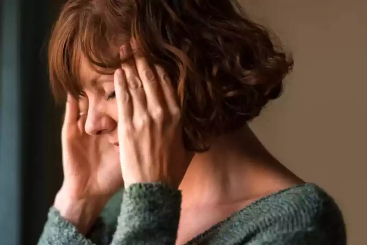 Dona amb expressió de dolor tocant-se el cap amb totes dues mans