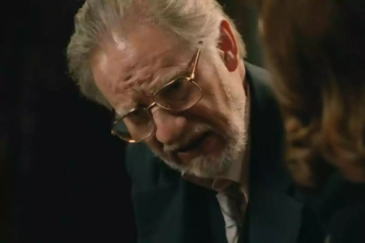 Pla curt de Nancho Novo amb ulleres i barba canosa inclinat cap endavant amb expressió seriosa mentre conversa amb una altra persona. Pla curt de Nancho Novo amb ulleres i barba canosa inclinat cap endavant amb expressió seriosa mentre conversa amb una altra persona.