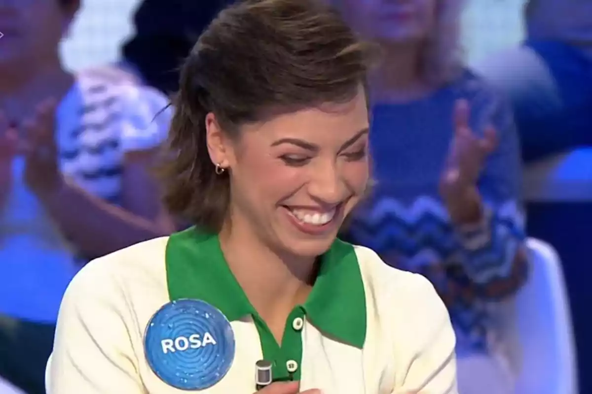 Rosa somrient amb el nom Rosa en una xapa blava durant un programa de televisió amb públic de fons. Captura de 'Pasapalabra' Rosa somrient amb el nom Rosa en una xapa blava durant un programa de televisió amb públic de fons. Captura de 'Pasapalabra'
