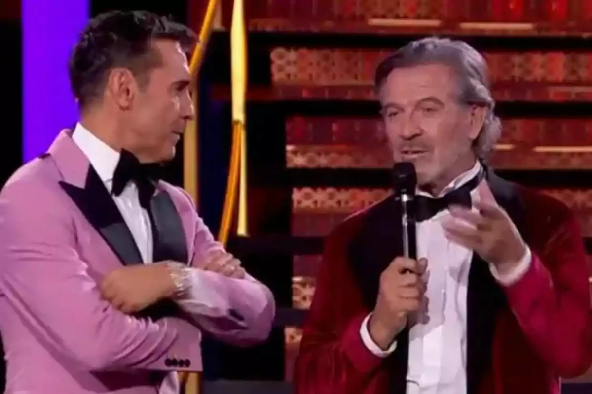 Jesús Vázquez i Pepe Navarro, elegantment vestits, conversen en un escenari il·luminat de Ballant amb les estrelles; un d’ells sosté un micròfon mentre l’altre creua els braços. Jesús Vázquez i Pepe Navarro, elegantment vestits, conversen en un escenari il·luminat de Ballant amb les estrelles; un d’ells sosté un micròfon mentre l’altre creua els braços.