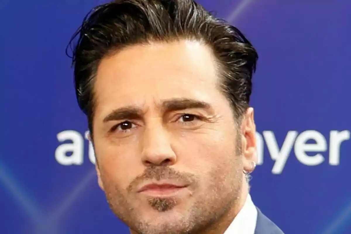 Primer pla de David Bustamante amb expressió seriosa davant d’un fons blau. Primer pla de David Bustamante amb expressió seriosa davant d’un fons blau.