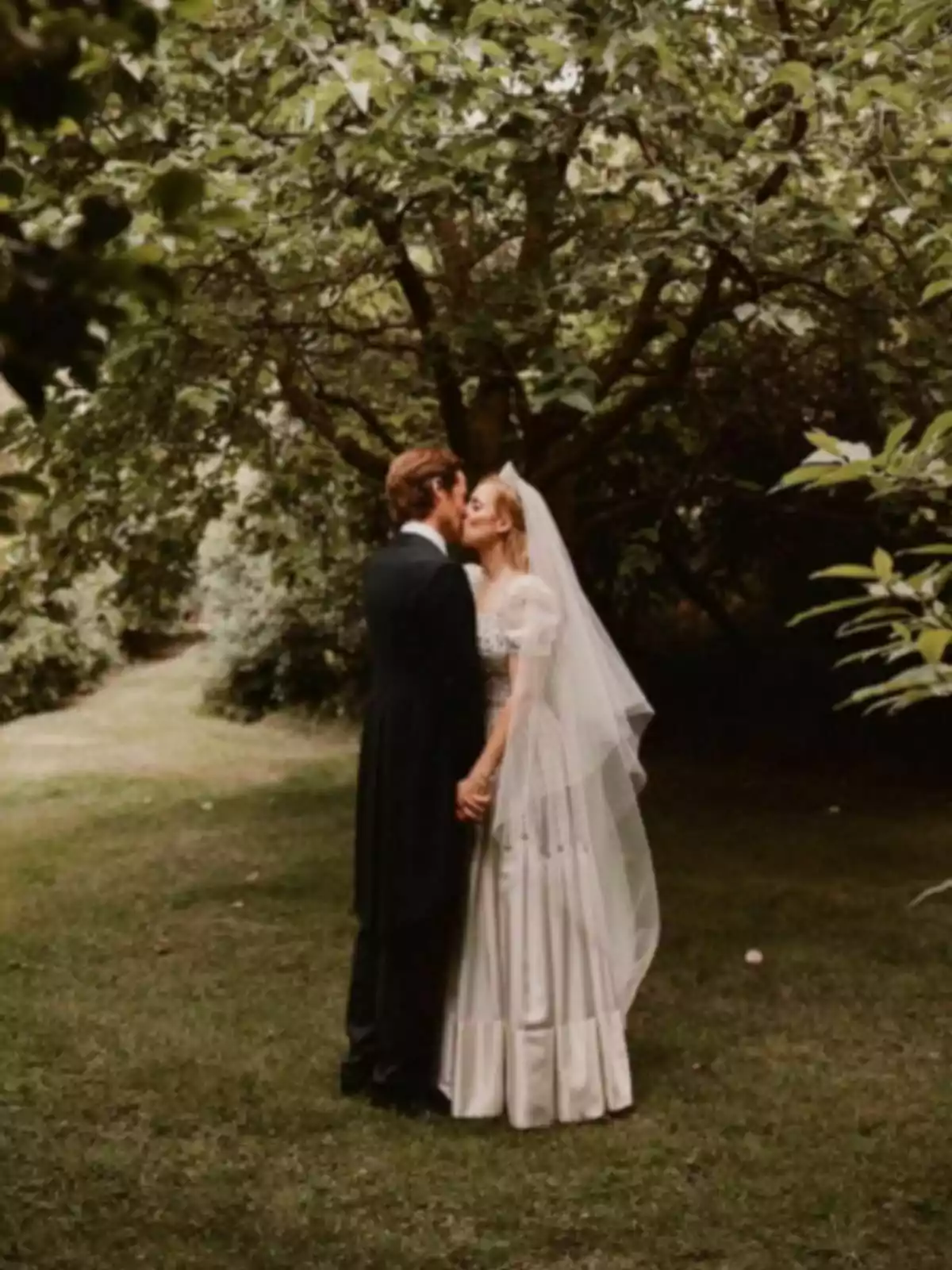 Edoardo Mapelli i Beatriz de York acabats de casar-se es fan un petó en un jardí envoltat d’arbres