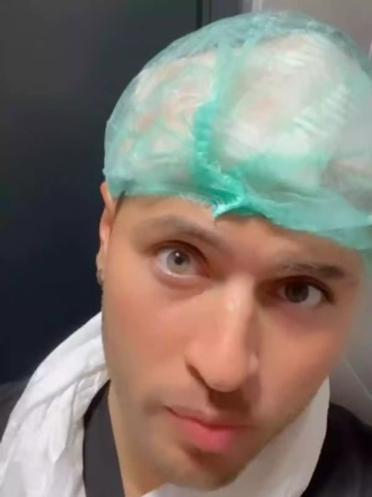 Persona jove amb gorra quirúrgica verda i bata blanca mirant a la càmera