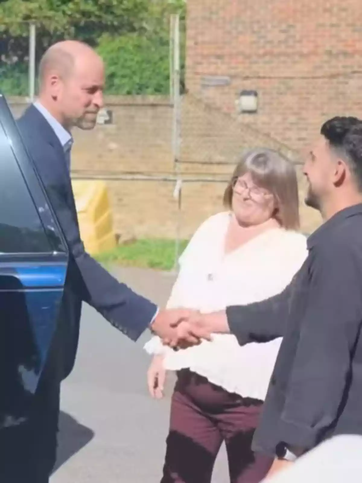 El príncep Guillem i dues persones més interactuen a l’aire lliure mentre dues d’elles es donen la mà i la tercera observa somrient. El príncep Guillem i dues persones més interactuen a l’aire lliure mentre dues d’elles es donen la mà i la tercera observa somrient.