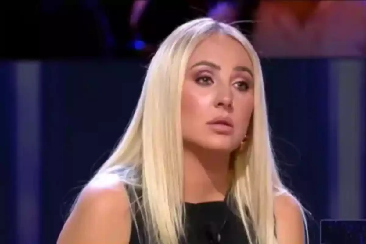 Rocío Flores, cabell ros llarg i llis amb expressió seriosa, asseguda en un estudi de televisió amb fons fosc. Rocío Flores, cabell ros llarg i llis amb expressió seriosa, asseguda en un estudi de televisió amb fons fosc.