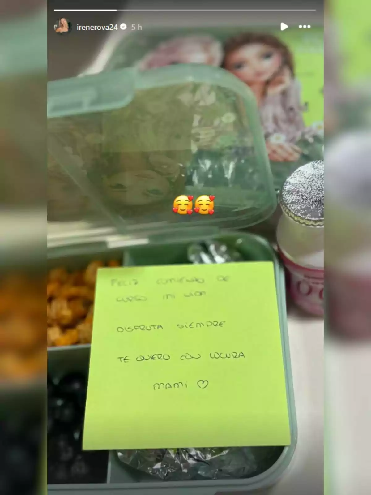 Llauna infantil verda amb compartiments per al menjar, una nota escrita a mà sobre paper groc i una beguda petita decorada, tot sobre una taula. Llauna infantil verda amb compartiments per al menjar, una nota escrita a mà sobre paper groc i una beguda petita decorada, tot sobre una taula.