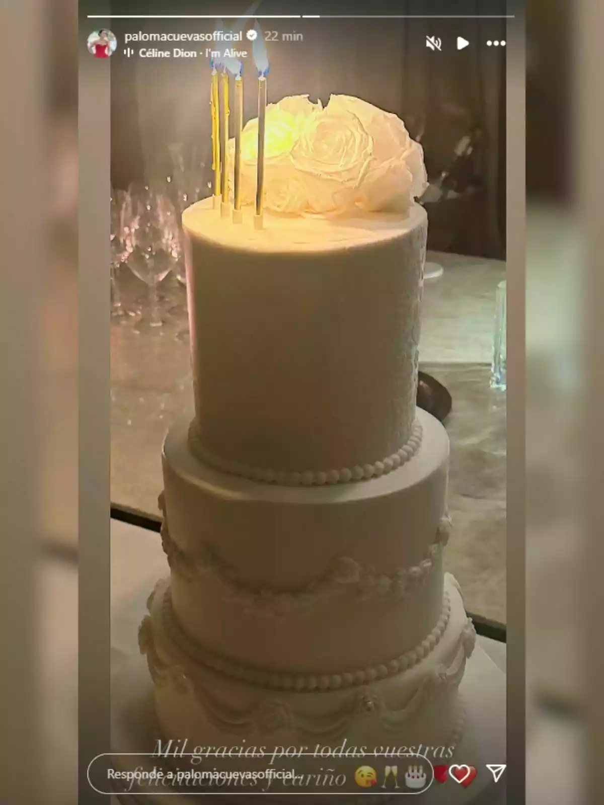 Pastís de tres pisos decorat amb perles i flors blanques, amb espelmes enceses a la part superior