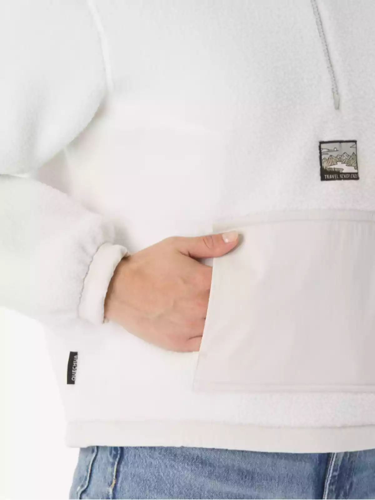 Persona amb jaqueta blanca de folre polar i butxaca frontal, portant texans i ficant una mà a la butxaca Persona amb jaqueta blanca de folre polar i butxaca frontal, portant texans i ficant una mà a la butxaca