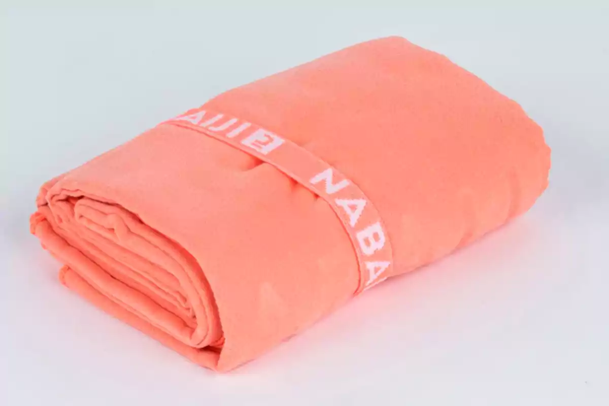 Tovallola de microfibra de color corall enrotllada i subjectada amb una banda elàstica