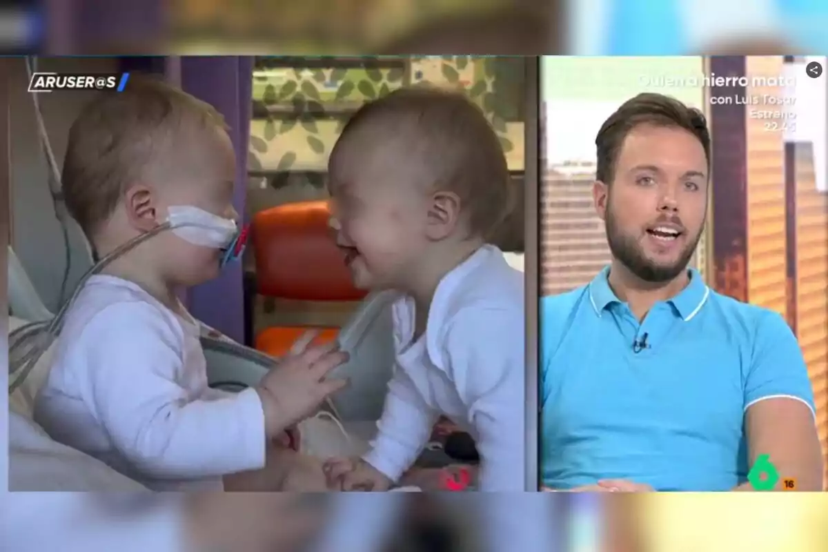 Dos nadons petits interactuen en una habitació d’hospital mentre un home jove amb barba i samarreta blava parla en un programa de televisió.