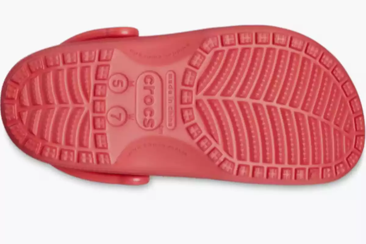 Sola de sandàlia Crocs de color rosa vista des de sota mostrant el disseny antilliscant i el nom de la marca al centre Sola de sandàlia Crocs de color rosa vista des de sota mostrant el disseny antilliscant i el nom de la marca al centre