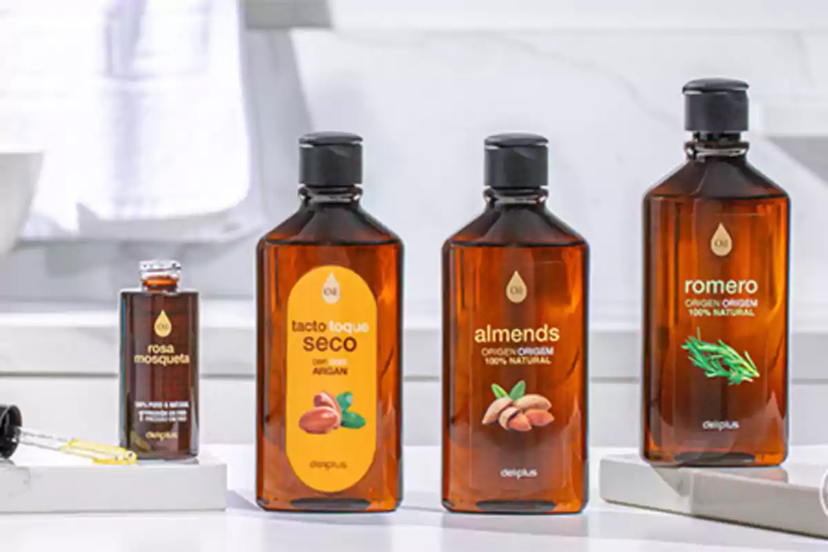 Quatre flascons d’olis naturals de la marca Deliplus estan alineats sobre una superfície blanca en un bany, cadascun amb etiquetes i colors diferents que representen rosa mosqueta, tacte sec amb argan, ametlles i romaní. Quatre flascons d’olis naturals de la marca Deliplus estan alineats sobre una superfície blanca en un bany, cadascun amb etiquetes i colors diferents que representen rosa mosqueta, tacte sec amb argan, ametlles i romaní.