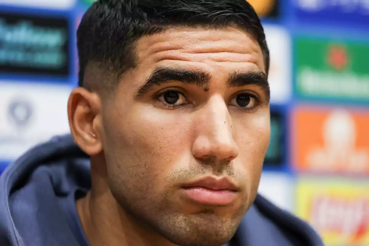Primer plano de Achraf Hakimi con expresión seria y fondo desenfocado de colores vivos Primer plano de Achraf Hakimi con expresión seria y fondo desenfocado de colores vivos