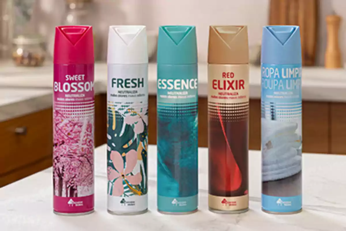 Cinco aerosoles aromatizantes de diferentes fragancias están alineados sobre una encimera de cocina