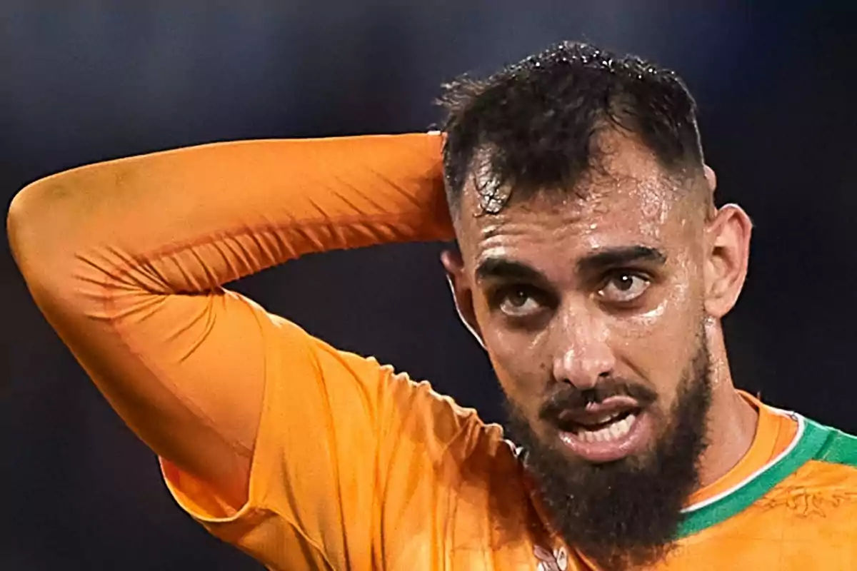 Borja Iglesias, con camiseta naranja y barba, luciendo expresión de cansancio mientras se toca la cabeza Borja Iglesias, con camiseta naranja y barba, luciendo expresión de cansancio mientras se toca la cabeza