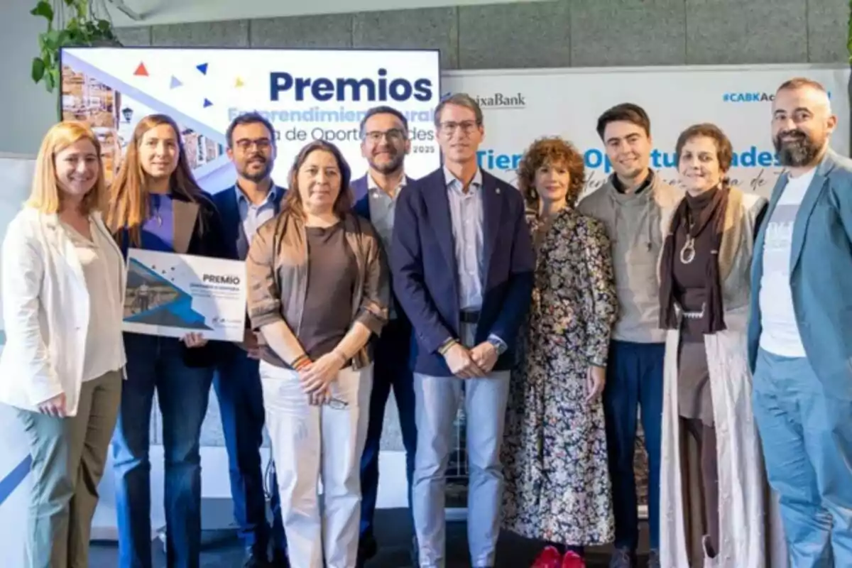 Grup de persones posant juntes en un esdeveniment de lliurament de premis d’emprenedoria rural, algunes d’elles sostenen un diploma i al fons s’observa una pantalla amb el nom de l’esdeveniment. Grup de persones posant juntes en un esdeveniment de lliurament de premis d’emprenedoria rural, algunes d’elles sostenen un diploma i al fons s’observa una pantalla amb el nom de l’esdeveniment.
