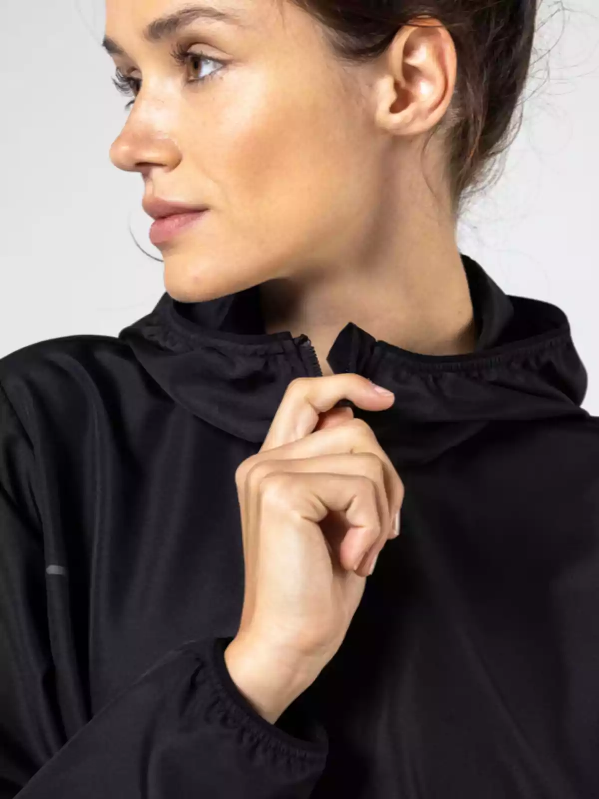 Dona de perfil amb jaqueta negra i cremallera fins al coll
