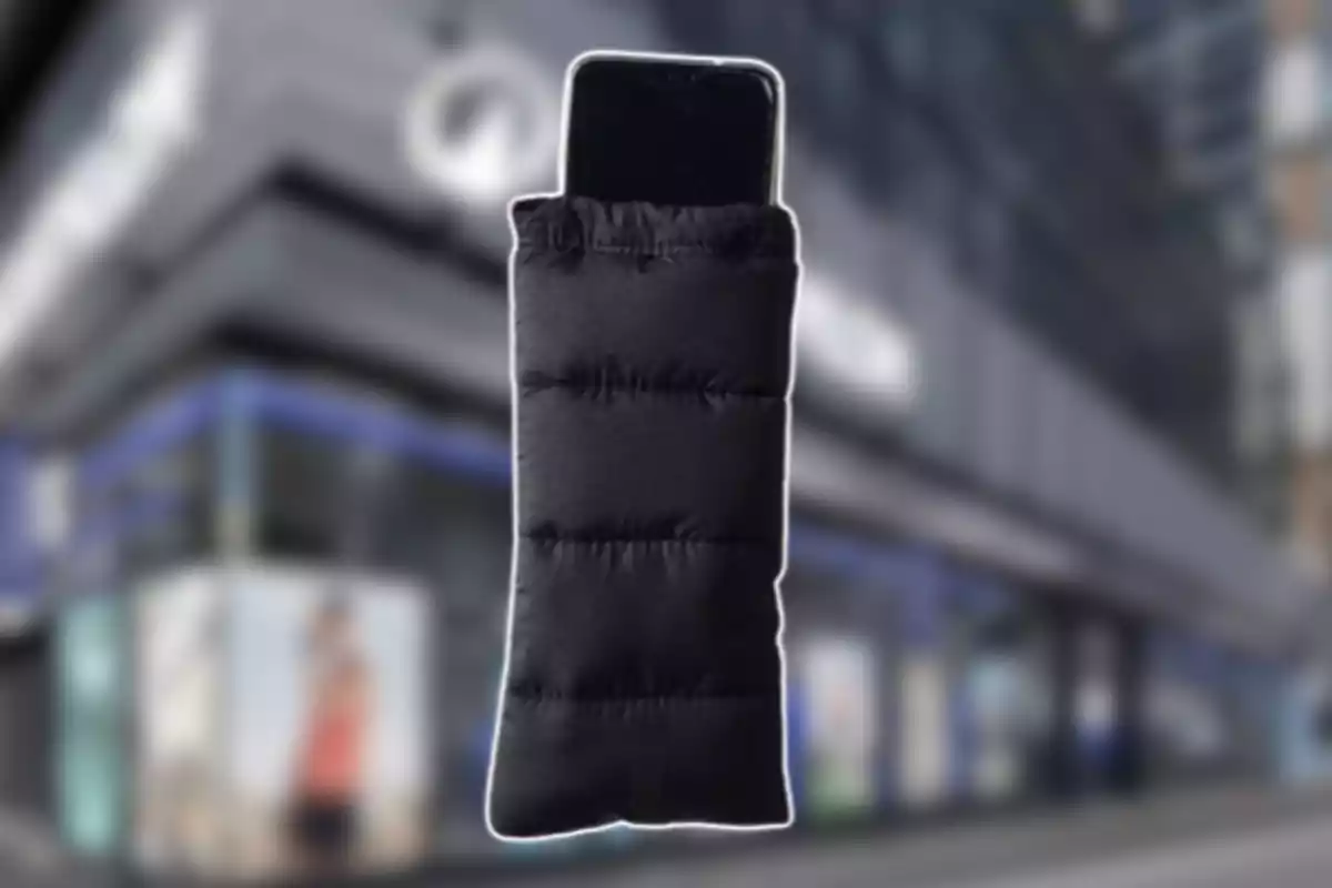 Un telèfon mòbil dins d’una funda encoixinada negra amb un fons d’edifici desenfocat