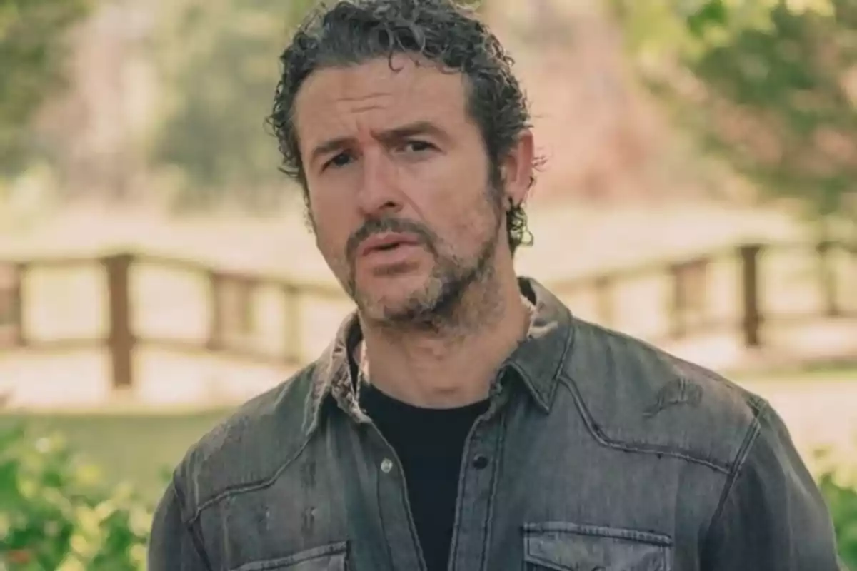 Diego Martín, de cabello rizado y barba con camisa de mezclilla, en un entorno al aire libre con árboles y una cerca de madera al fondo Diego Martín, de cabello rizado y barba con camisa de mezclilla, en un entorno al aire libre con árboles y una cerca de madera al fondo