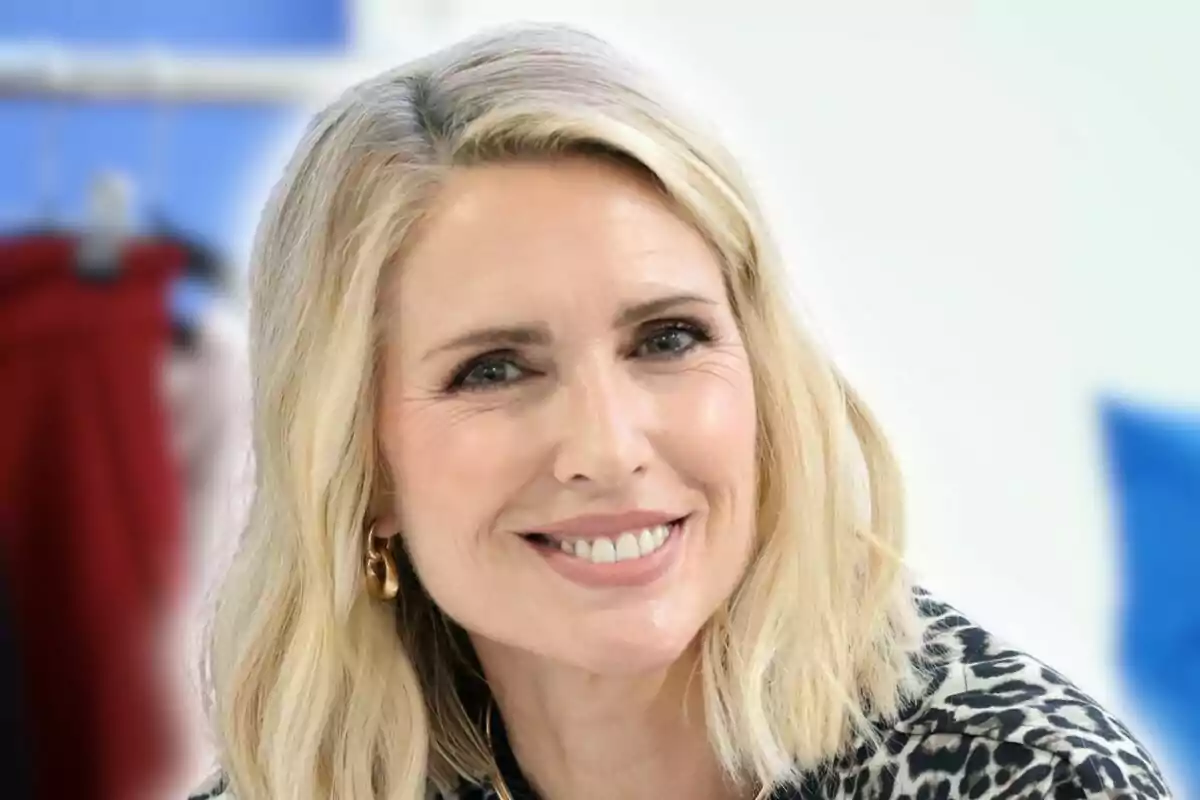 Dona rossa de cabell curt i ondulat somriu mentre mira a la càmera, porta una brusa d’estampat animal i arracades daurades. Dona rossa de cabell curt i ondulat somriu mentre mira a la càmera, porta una brusa d’estampat animal i arracades daurades.